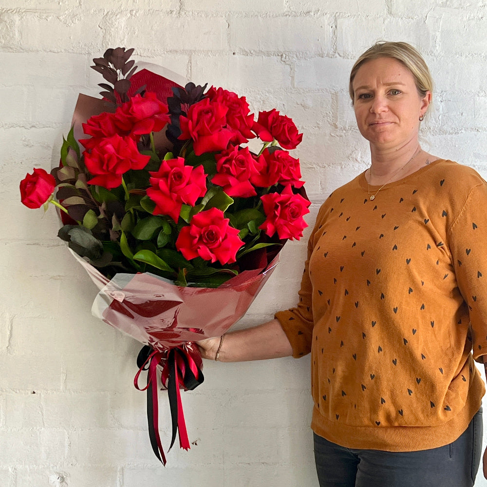 florist holing a dozen red roses