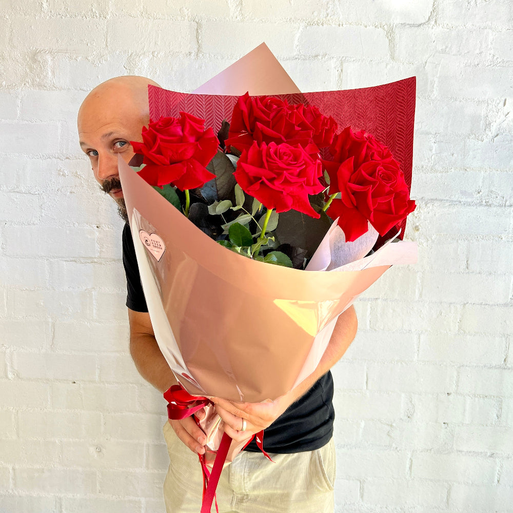 man holding 6 red rose bouquet
