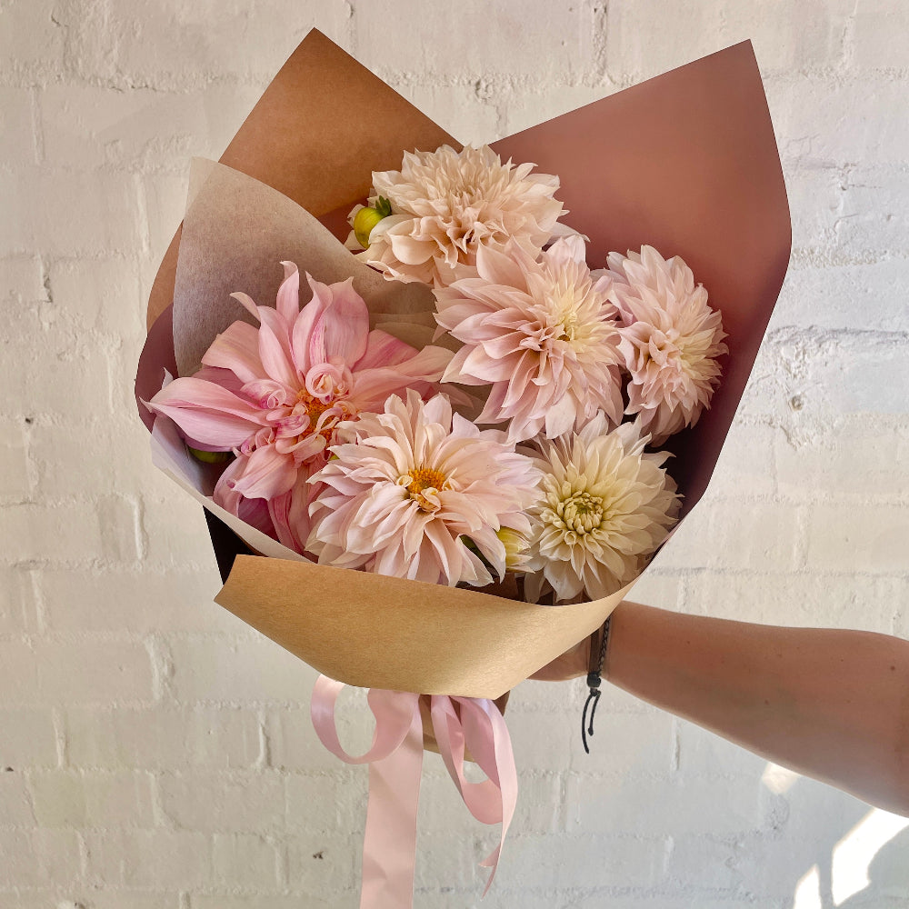 Bouquet of pink Dahlias wrapped in craft paper and a pink ribbon