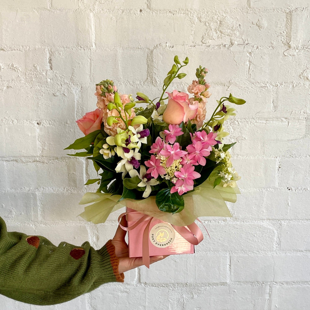 florist holding a pastel box arrangement