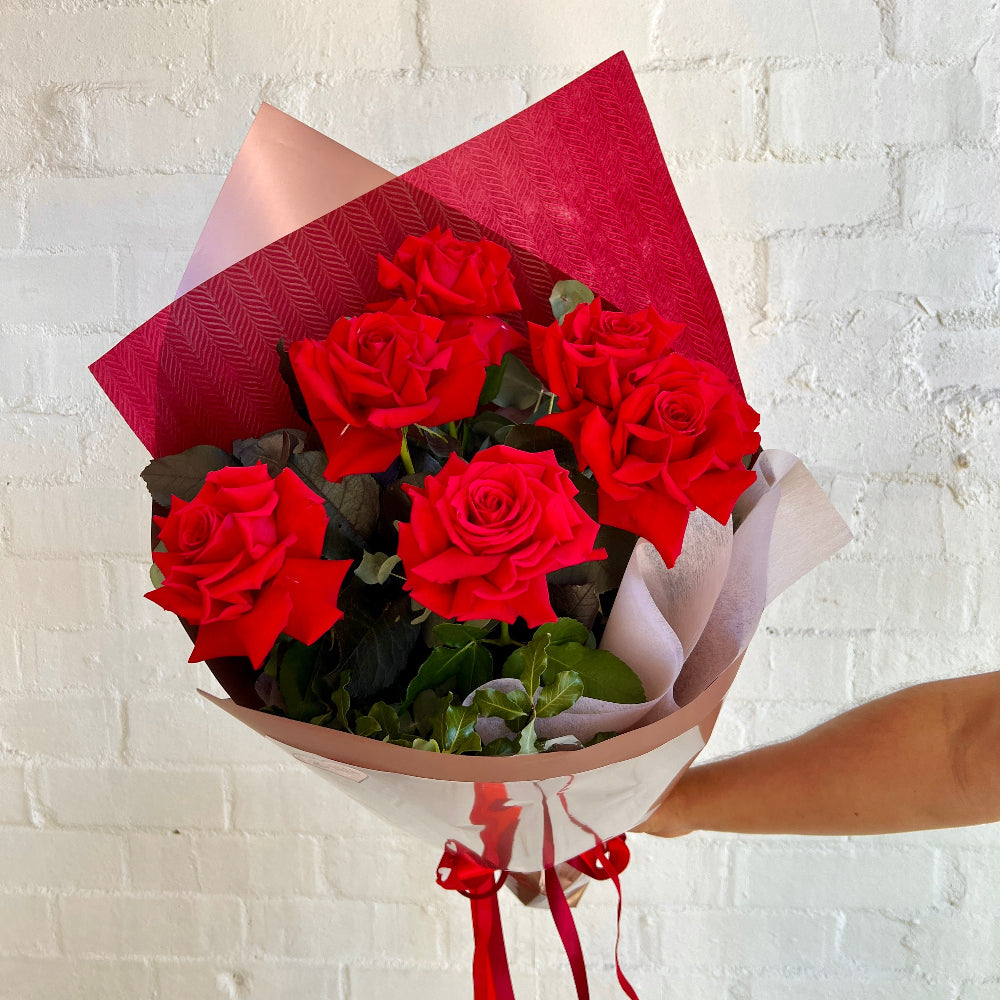 half a doze red roses in a gift wrapped bouquet