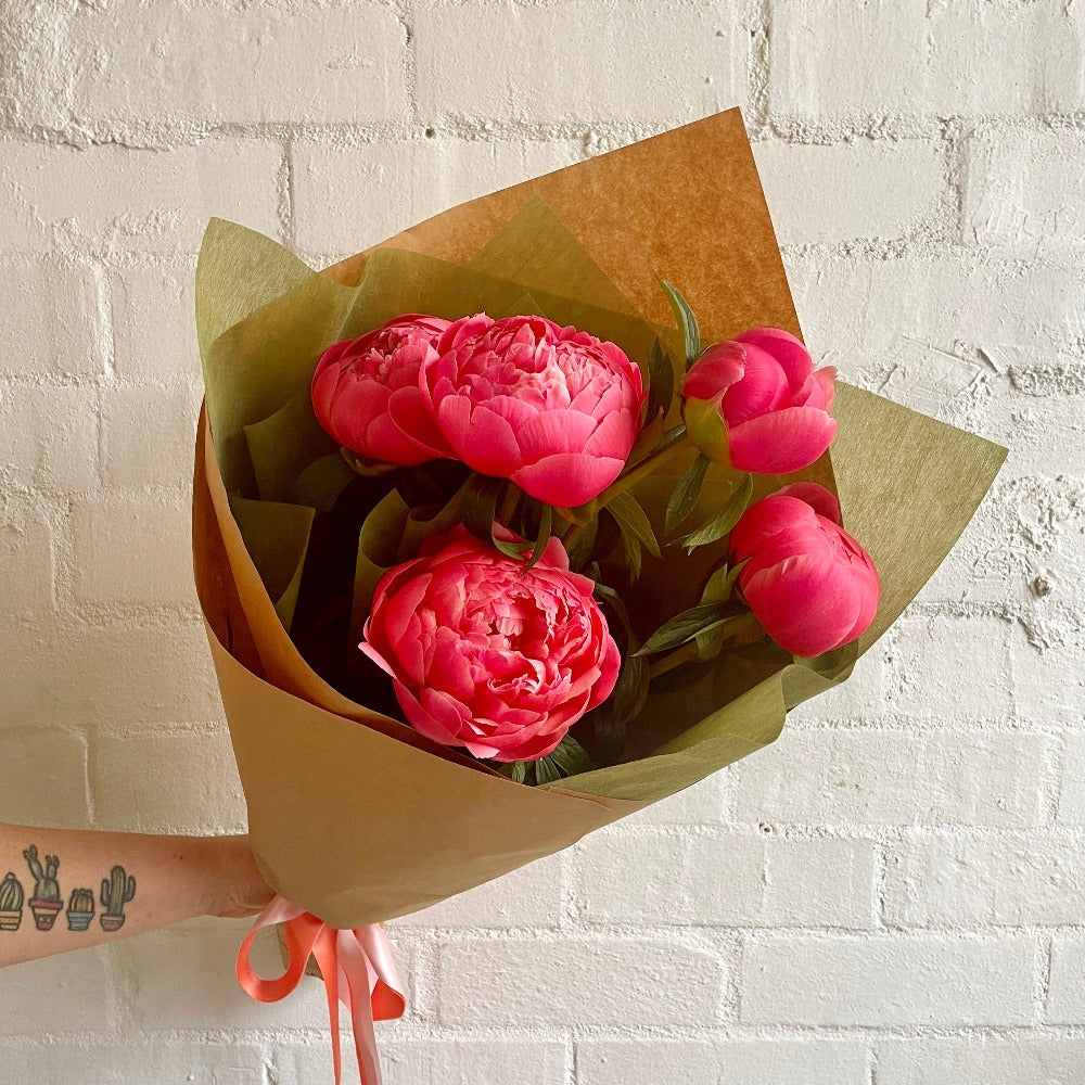 Hot pink peonies flower bouquet wrapped in brown craft paper 