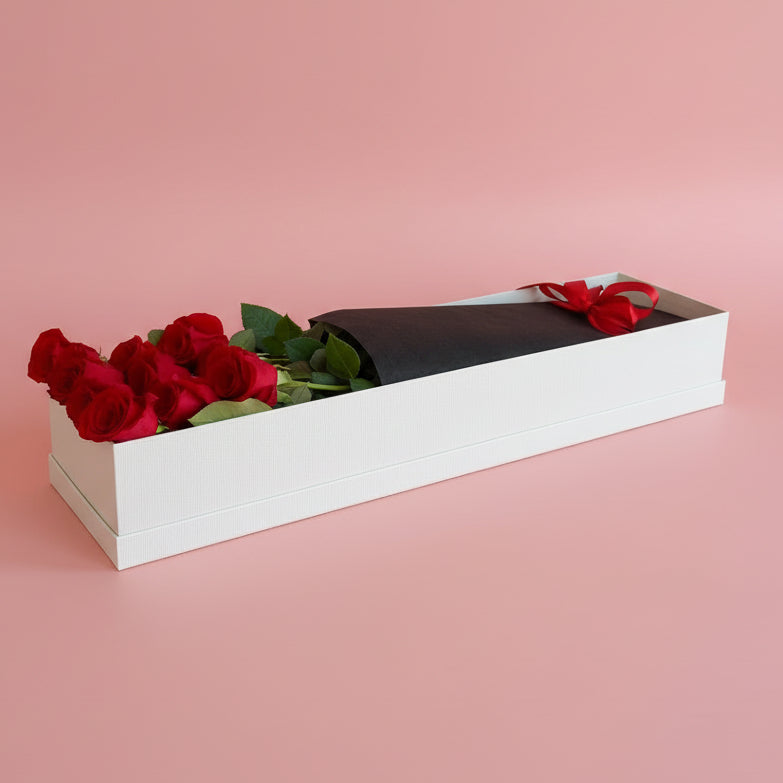 Red roses with black wrapping paper in a long white rectange gift box.