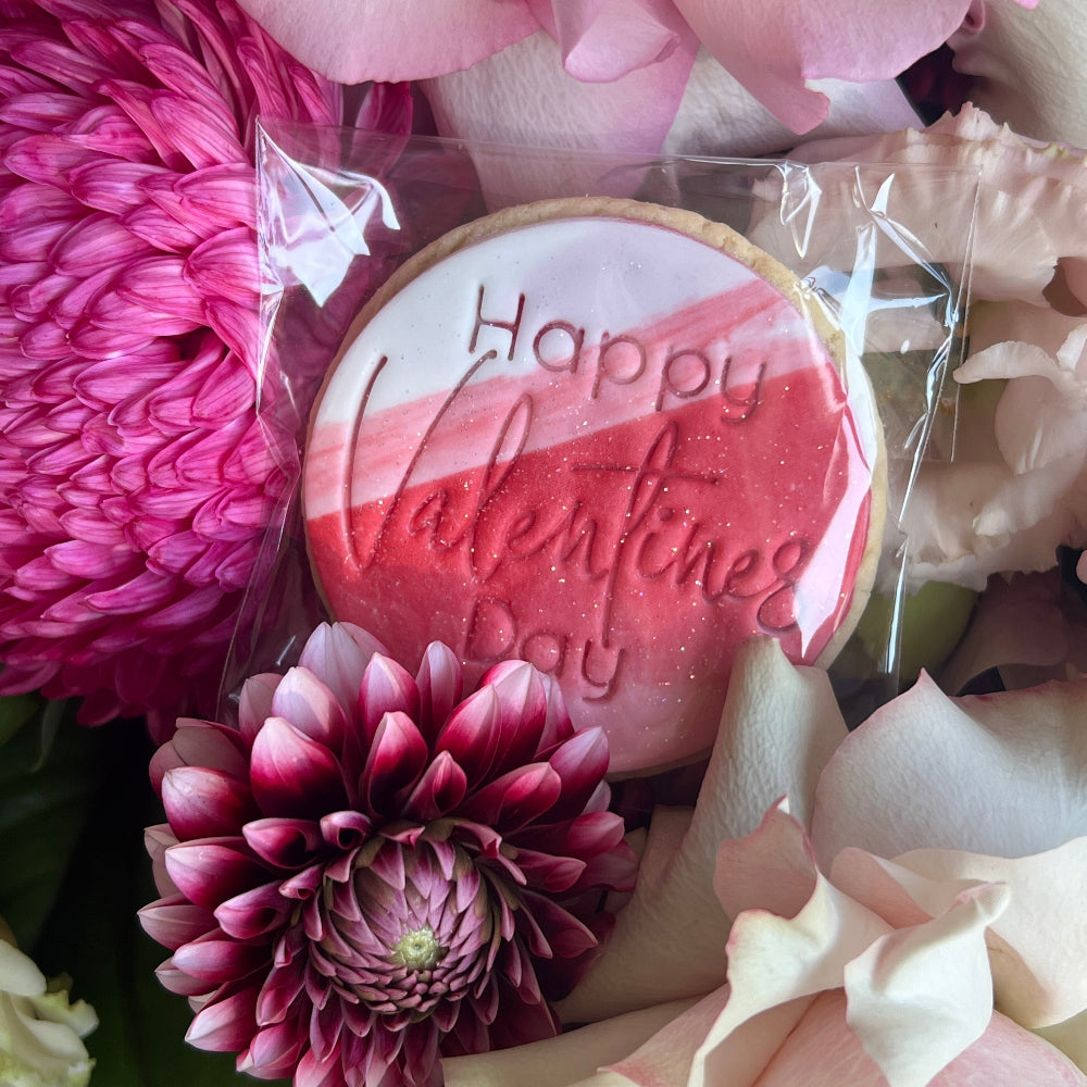 a pink, red and white cookie with the words Happy valentines day inscribed 