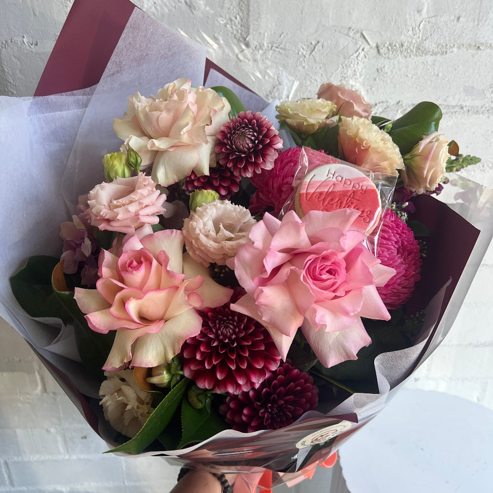 A mixed bouquet of florals with a Valentines day Cookie.