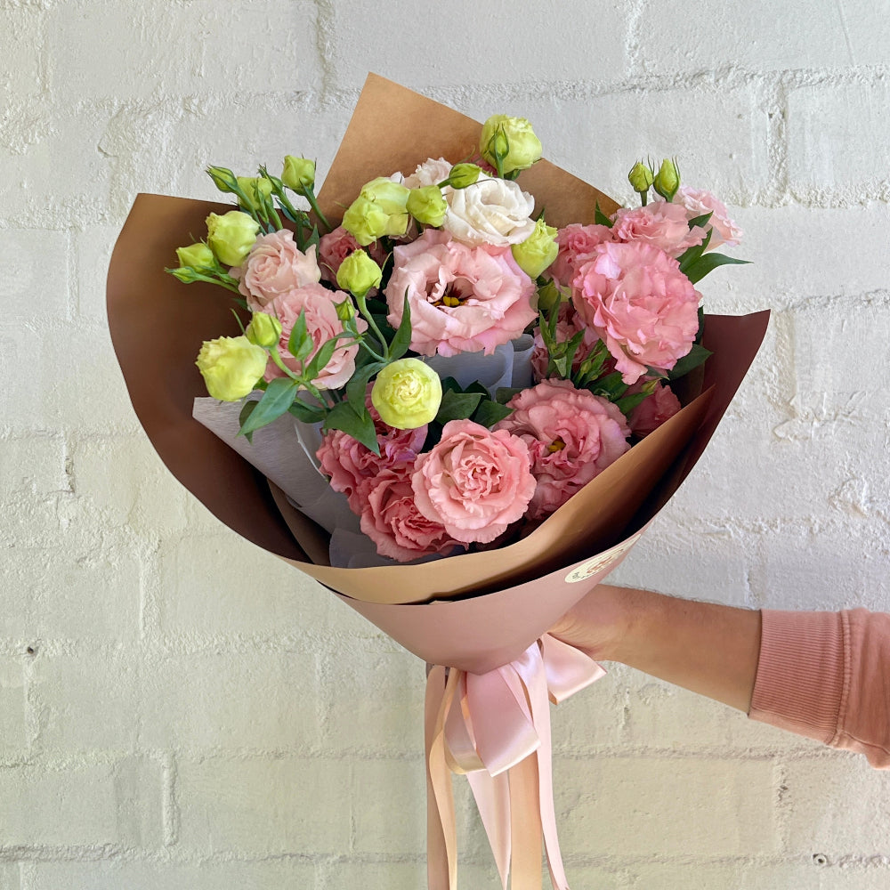 soft pink lisianthus bouquet wrapped in craft paper and pink ribbon