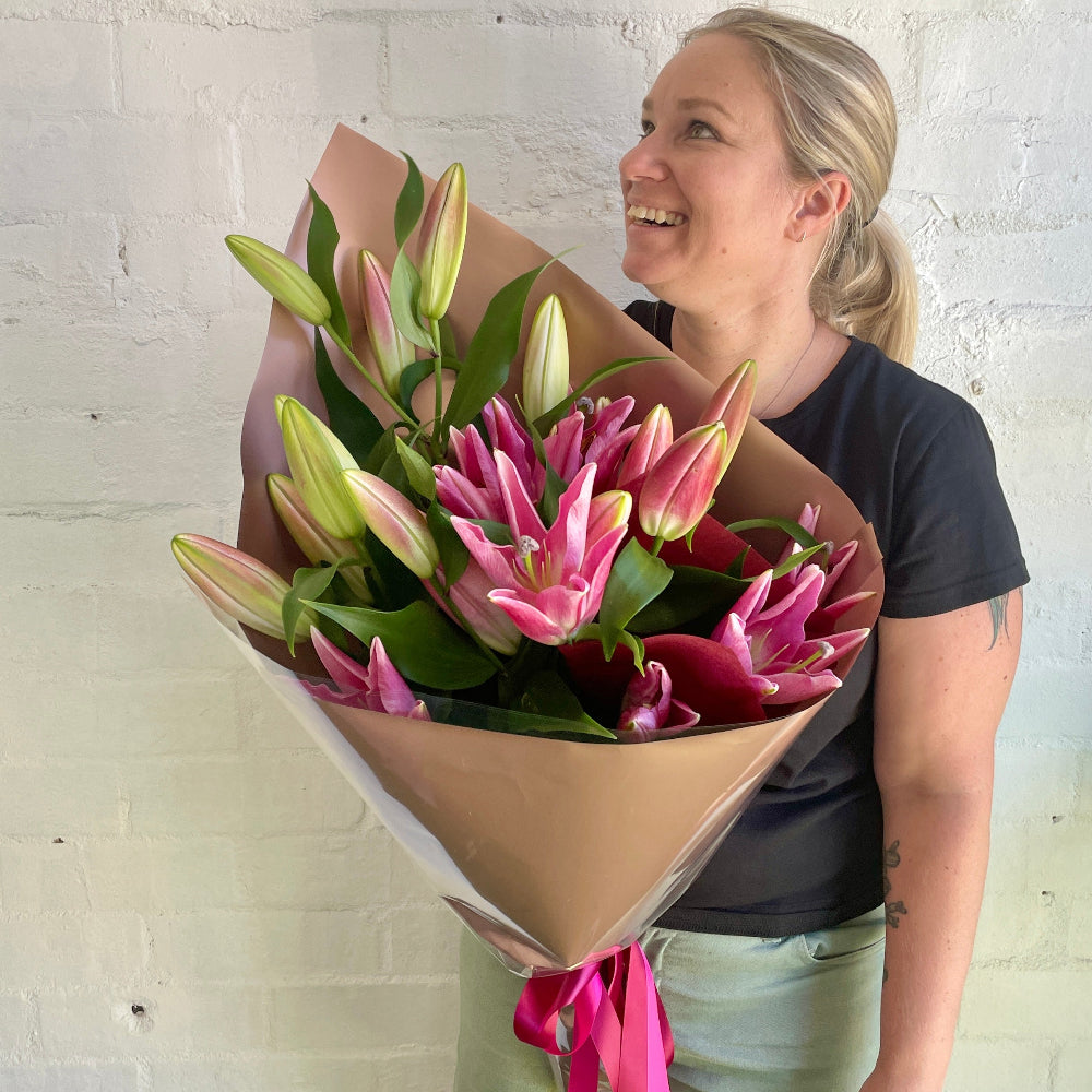 Florist holding a bouquet of pink oriental lilies