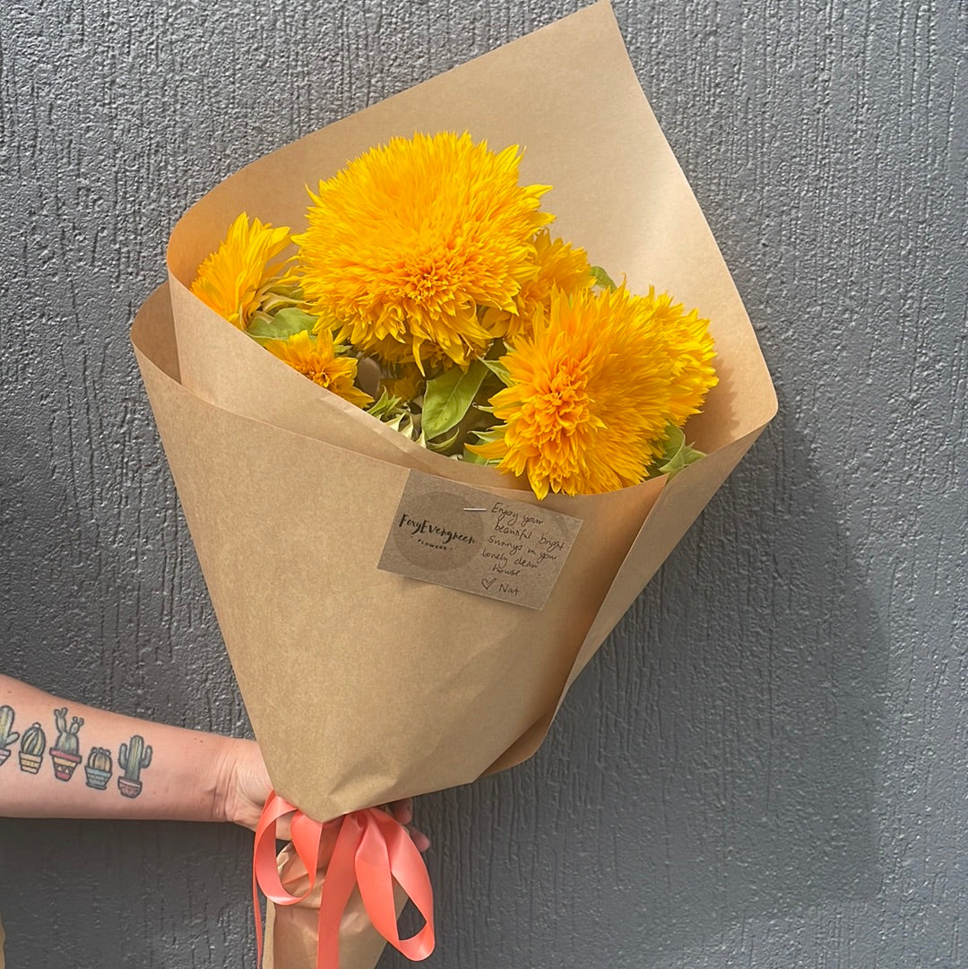 Fluffy Sunflower bouquet wrapped in brown craft paper with a orange bow